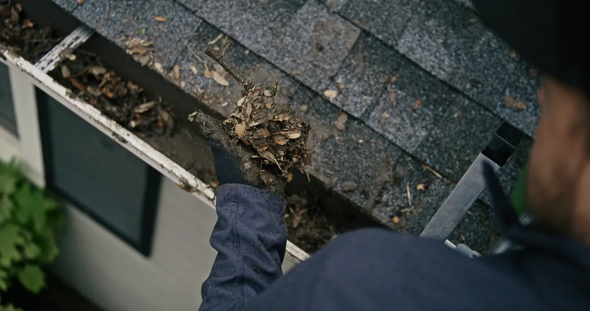 LeafFilter technician cleaning built-up debris out of a home's gutters