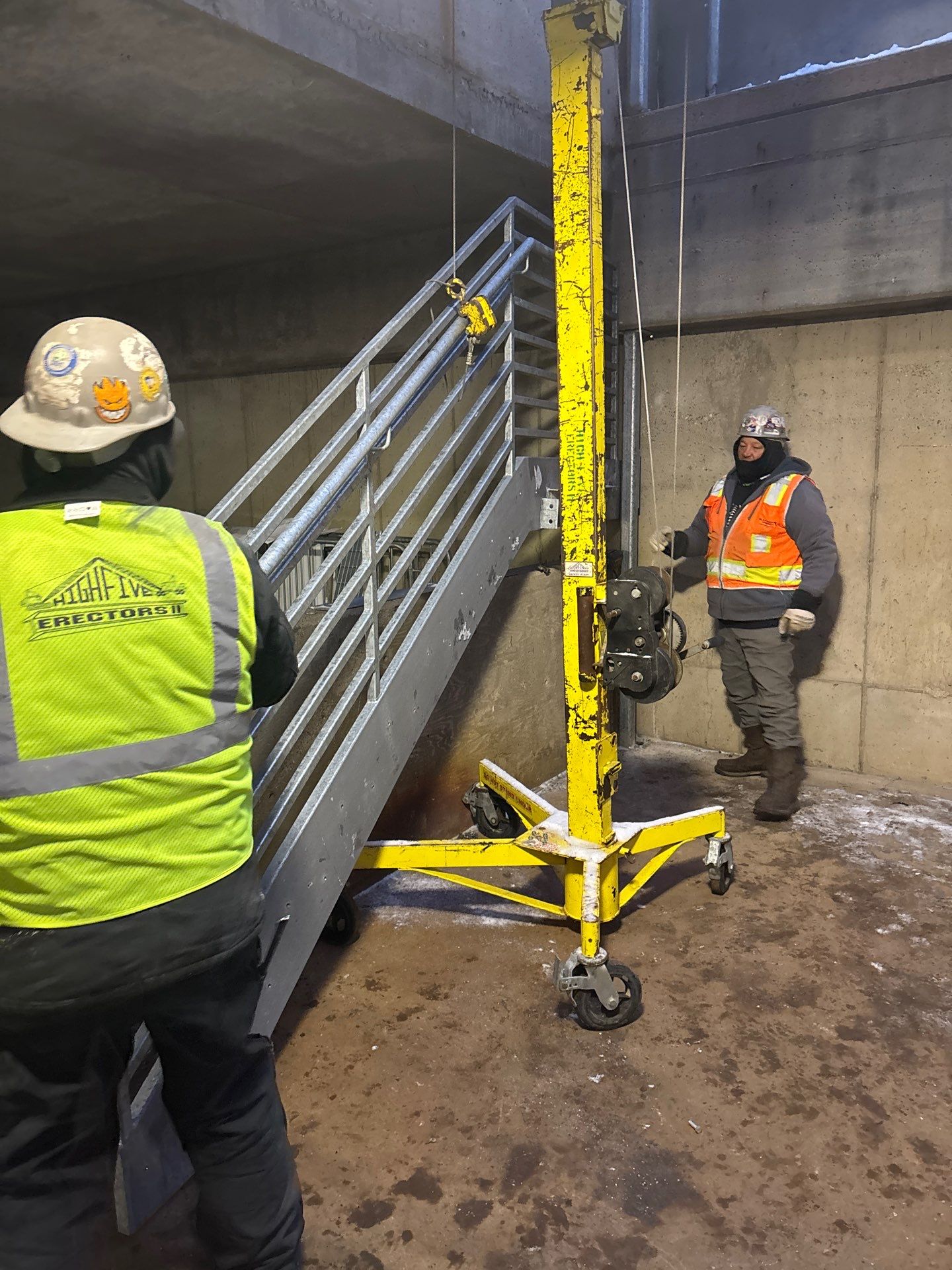 Workers in high-vis vests installing a new galvanized staircase at Bell Plaza, Bloomington, MN