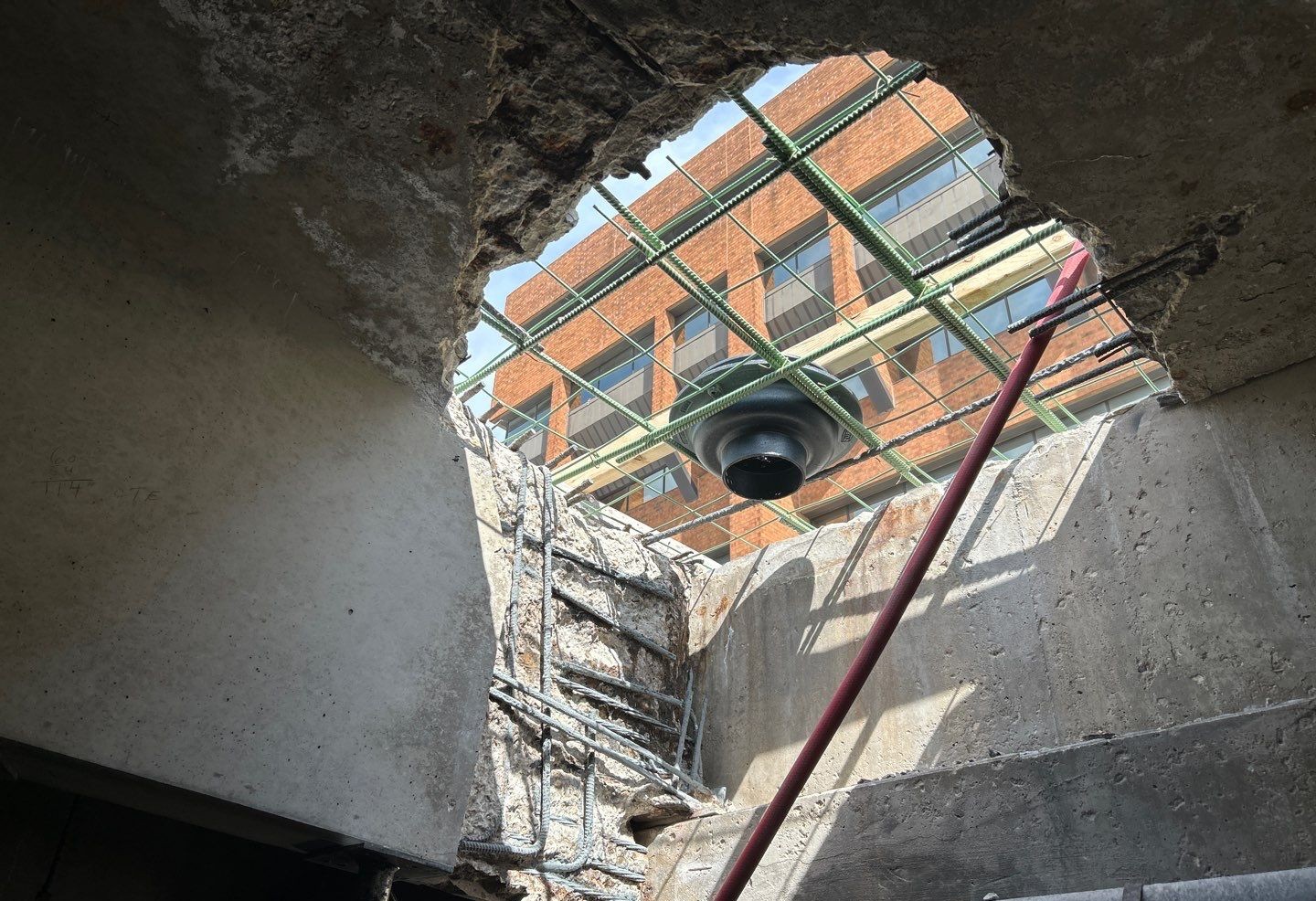 Demolished concrete slab with exposed rebar reinforcement during drain repair and structural concrete restoration at a commercial underground ramp in Milwaukee, WI