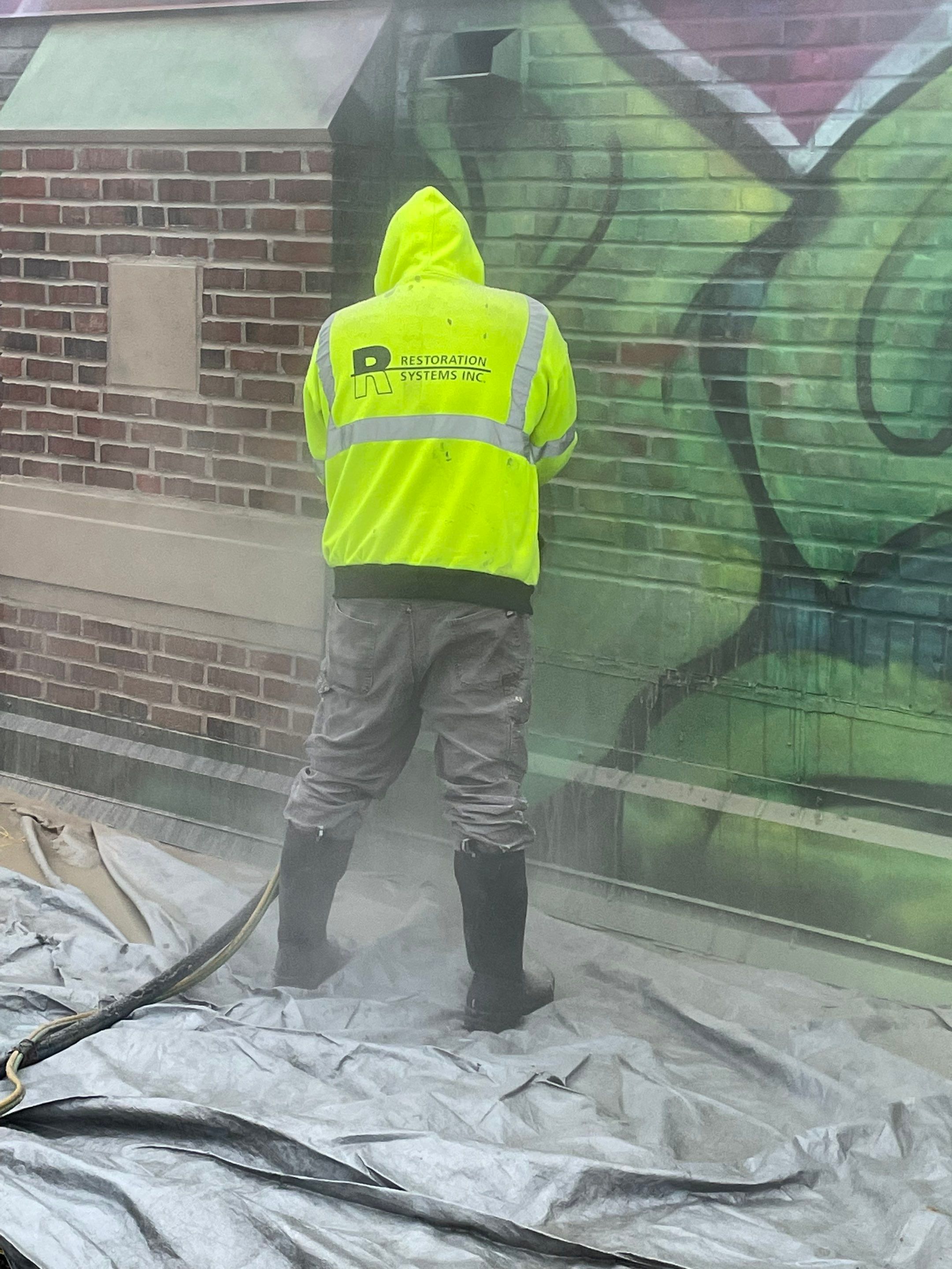 RSI employee performing graffiti removal on the Bio-Techne headquarters exterior