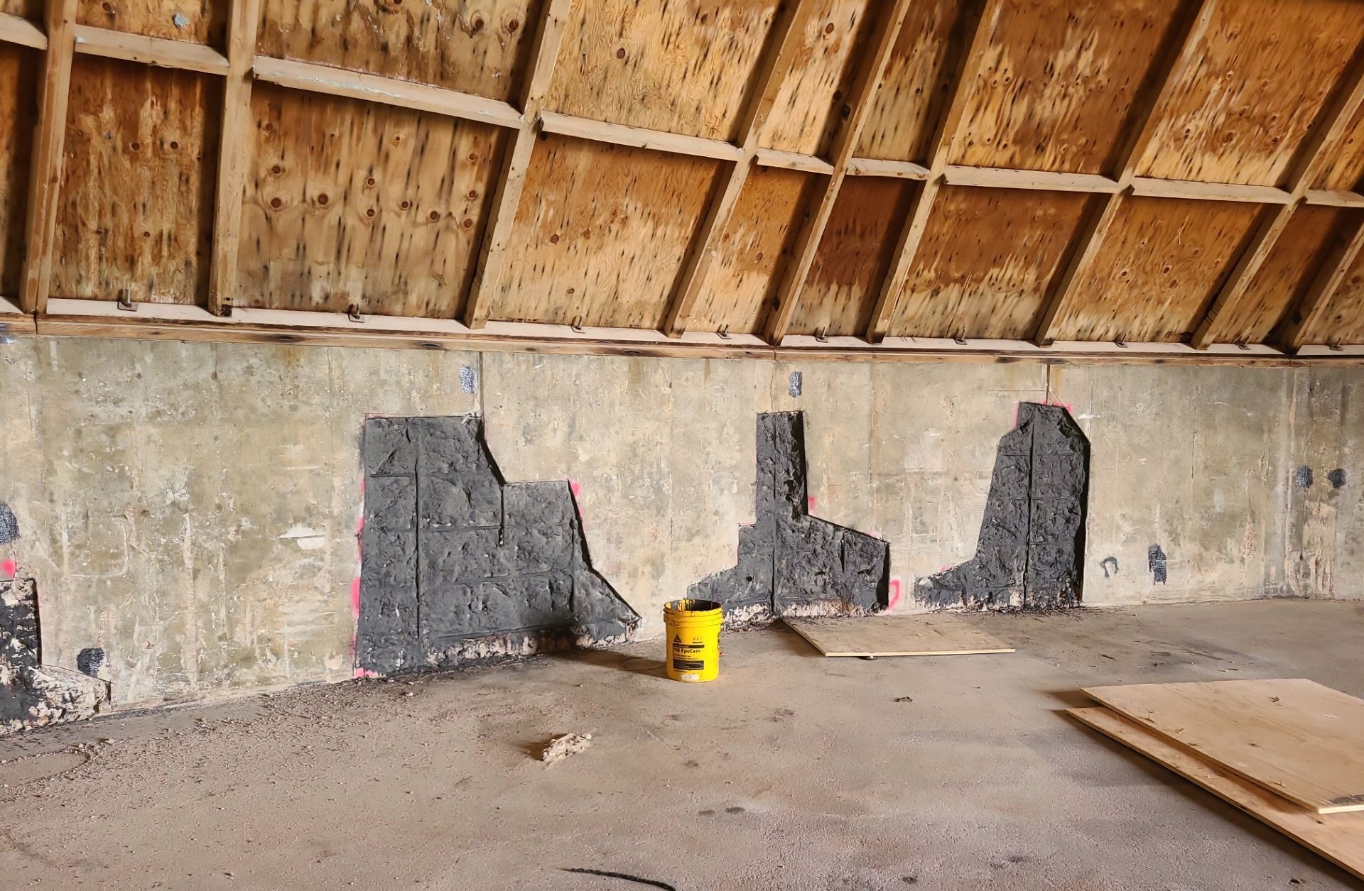 Three dark concrete repair patches applied to a damaged salt shed foundation wall during the RSI repair phase