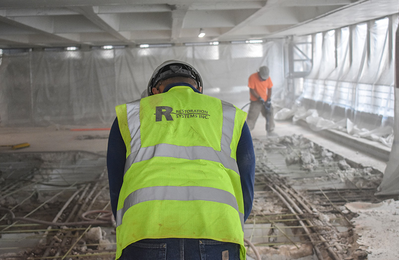 Worker cutting rebar with a power tool on a concrete parking surface