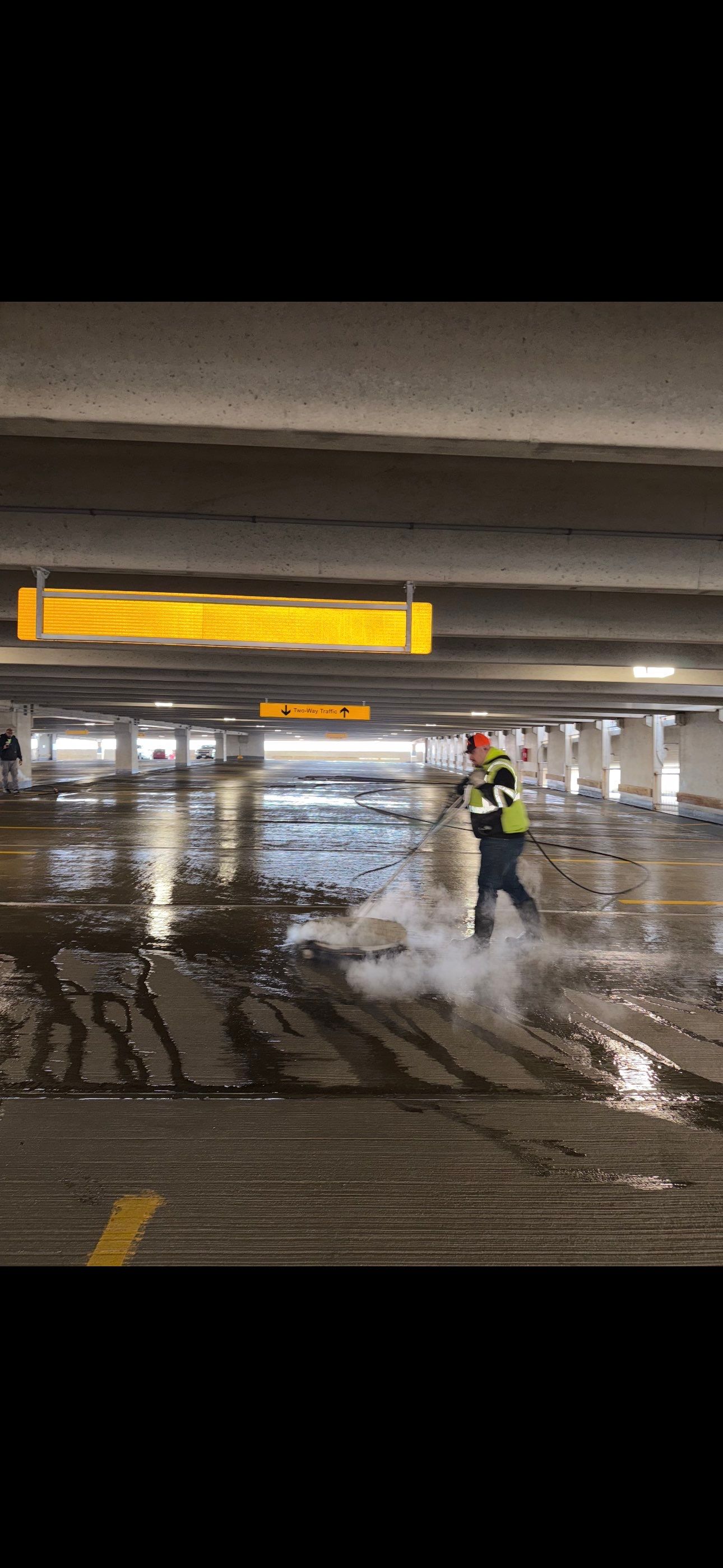 RSI worker operating a hot-water surface cleaner on an interior parking deck level in Madison, WI