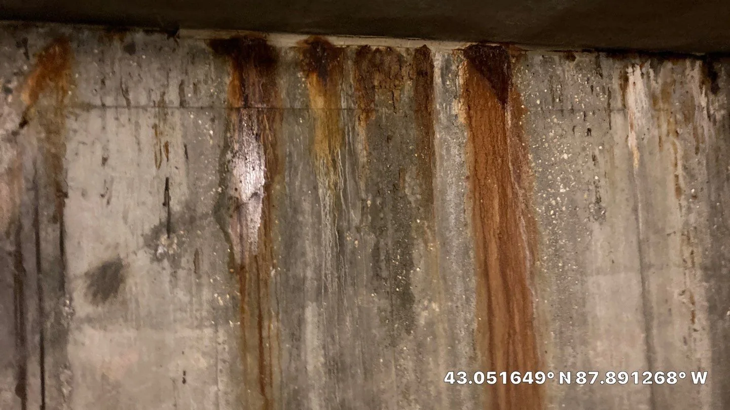 Rust and water staining on a concrete parking structure wall during commercial leak investigation