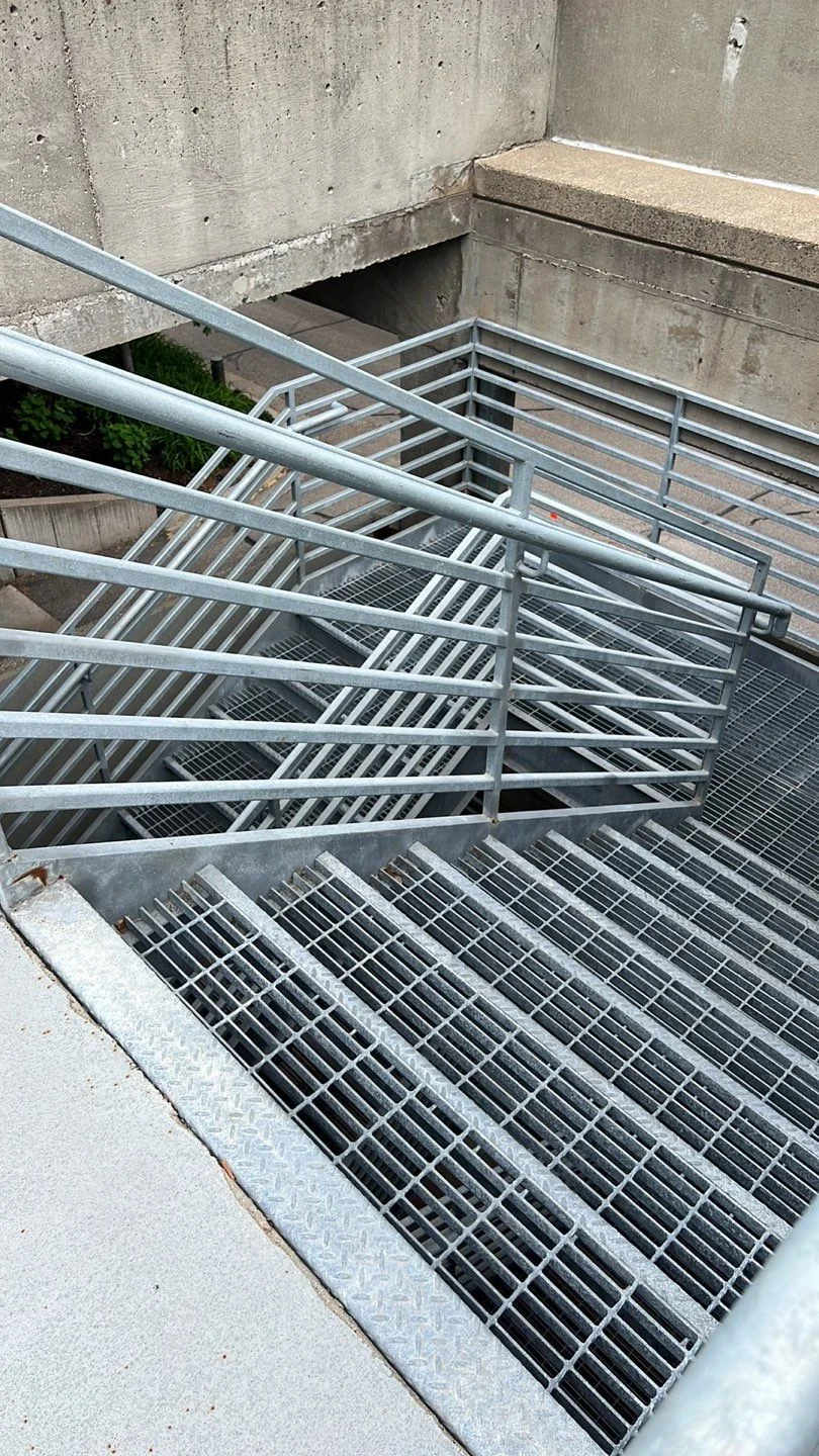 Galvanized commercial metal railing and landing system at a concrete stairwell