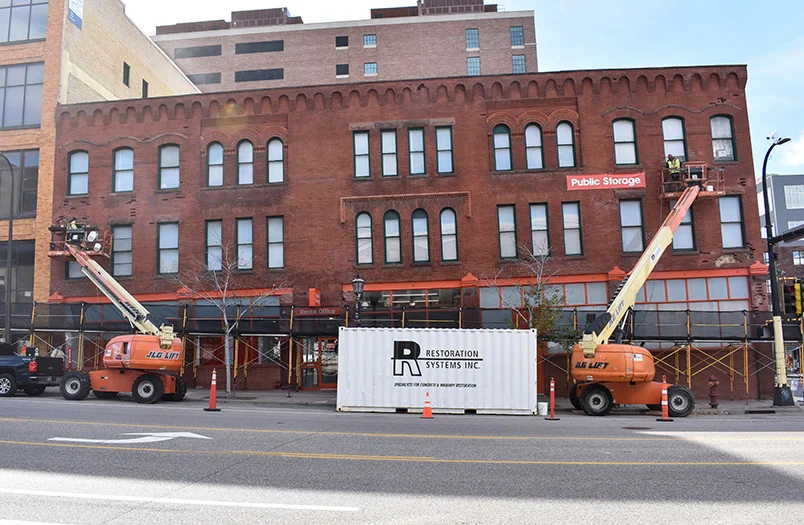 Boom lifts and sidewalk protection set up for exterior commercial facade restoration