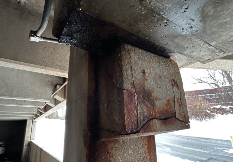 A beam-column connection on a Midwest parking structure showing severe freeze-thaw spalling with deep fracture planes and advanced rebar corrosion