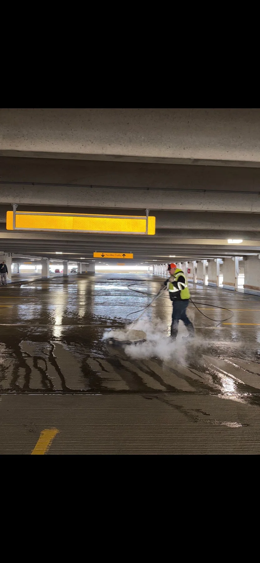 Technician pressure washing a commercial parking garage floor