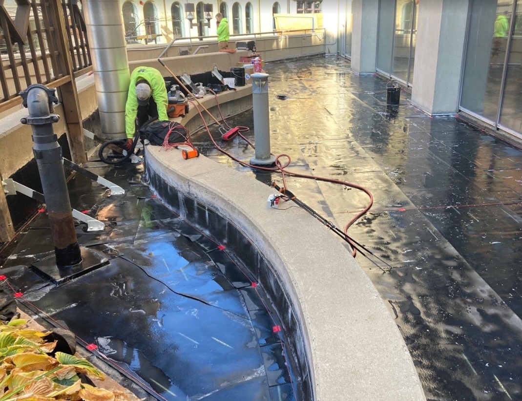 Hot applied waterproofing installation on Milwaukee plaza deck showing professional membrane application