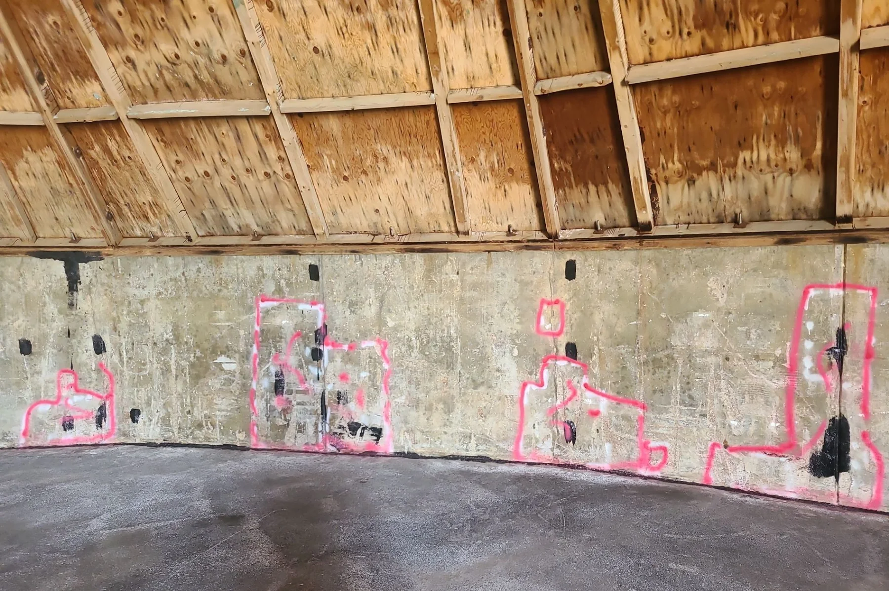 Pink layout markings on a salt-shed concrete wall identifying repair zones before an industrial protective coating is reinstalled