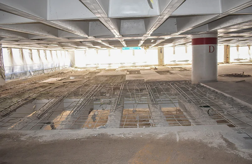 Open parking deck bay with concrete repair areas prepared for pothole repair and resurfacing