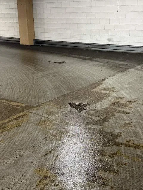 Parking deck pedestrian walking surface showing a spalled concrete pocket and chloride staining along the slab edge