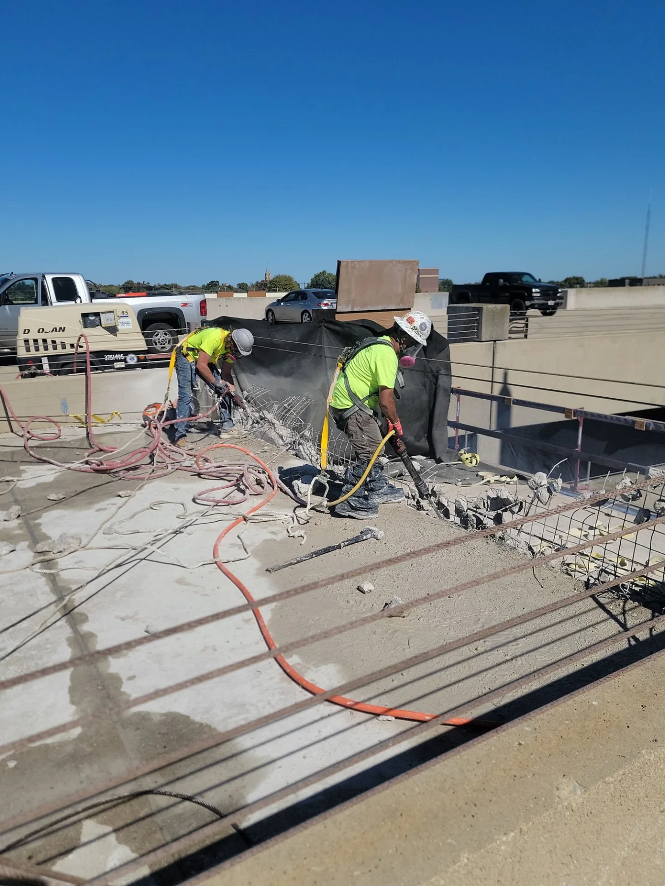 RSI crew demolishing a deteriorated concrete vehicle barrier at the parking deck edge in Appleton, Wisconsin, with exposed reinforcing steel visible across the slab