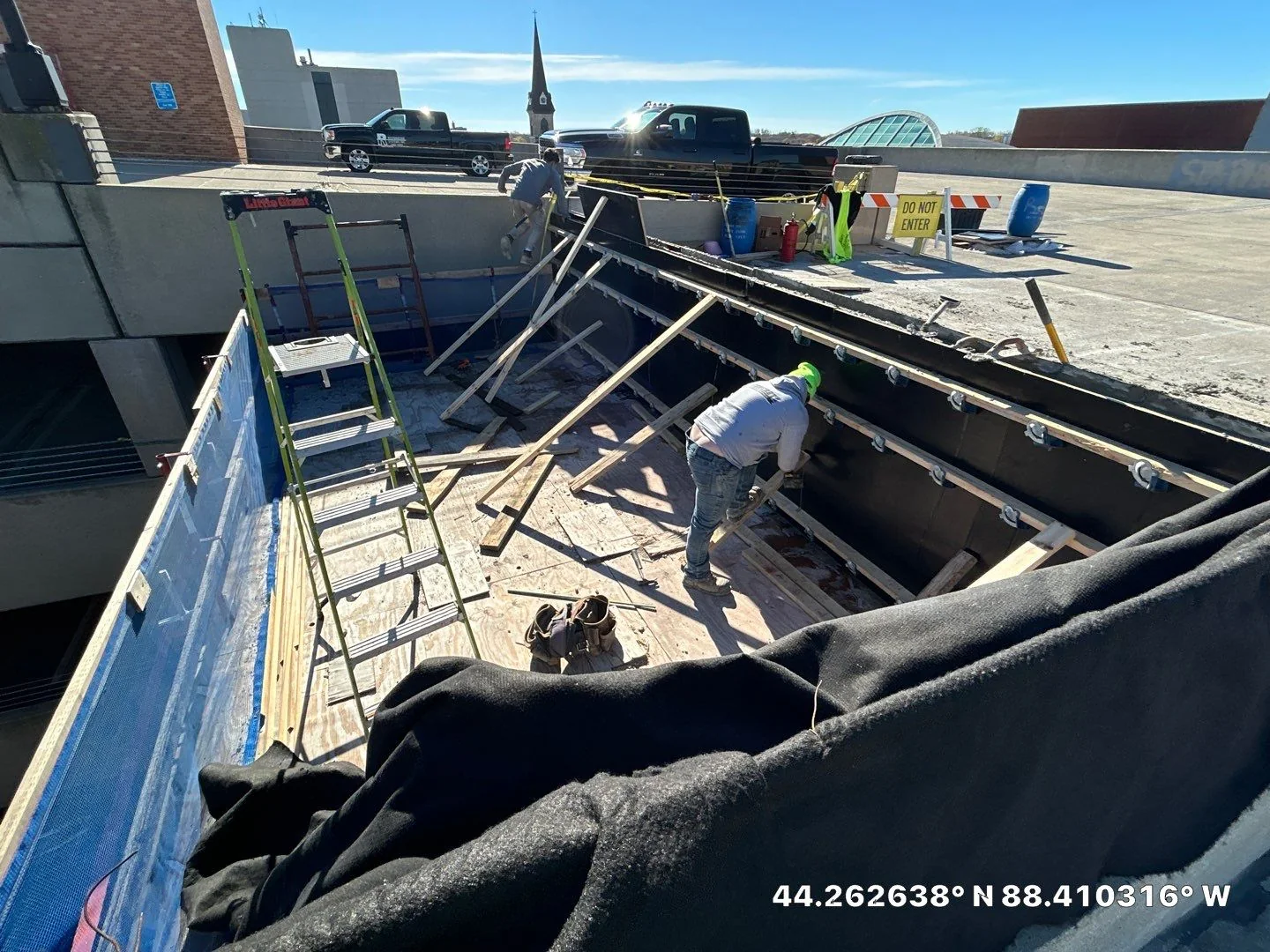 RSI crew rebuilding a cast-in-place concrete vehicle barrier on a Wisconsin parking deck, with form work and shoring visible at the slab edge