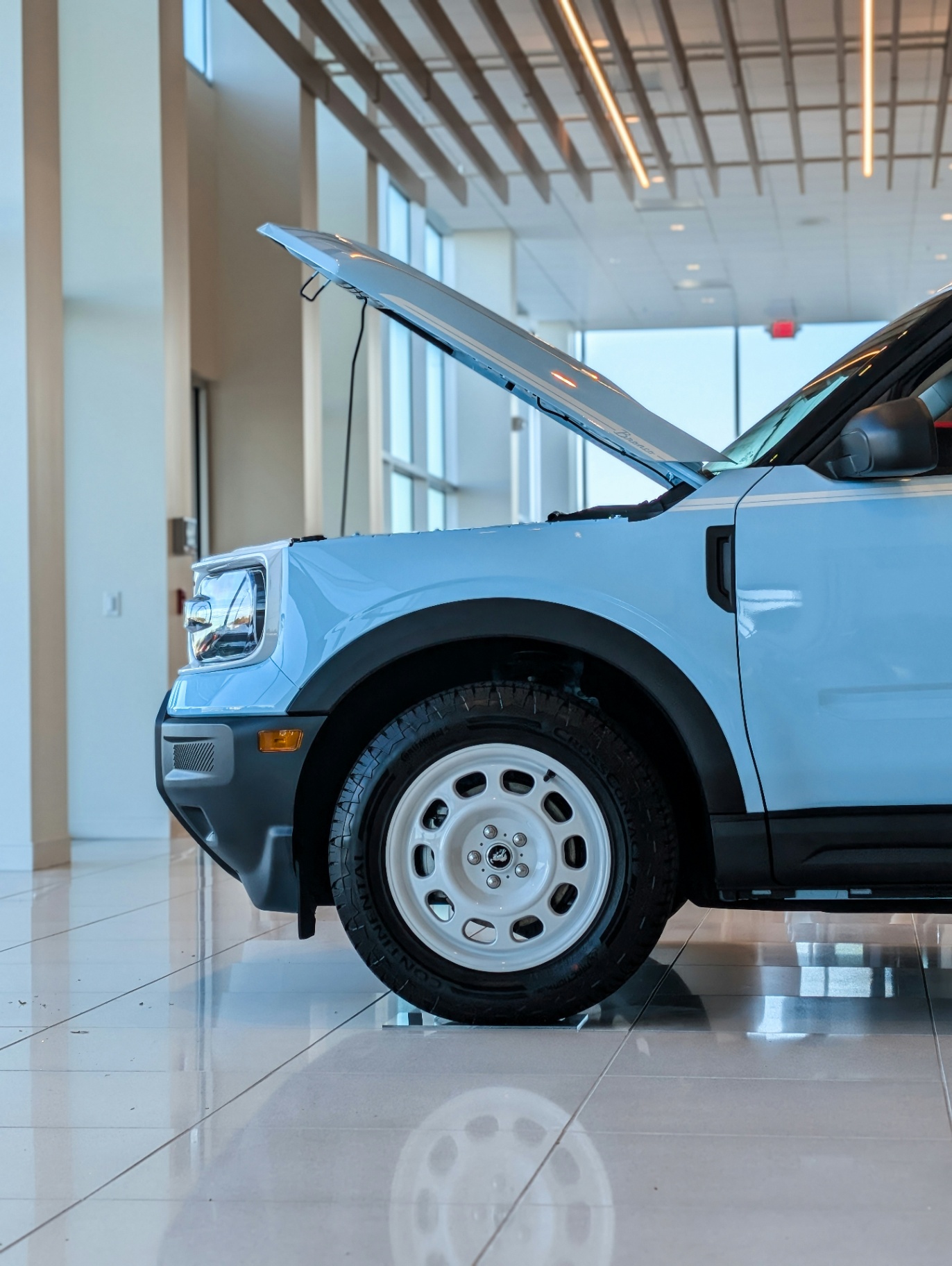 Hood open on an SUV on a showroom floor, revealing the engine bay during a pre-purchase inspection